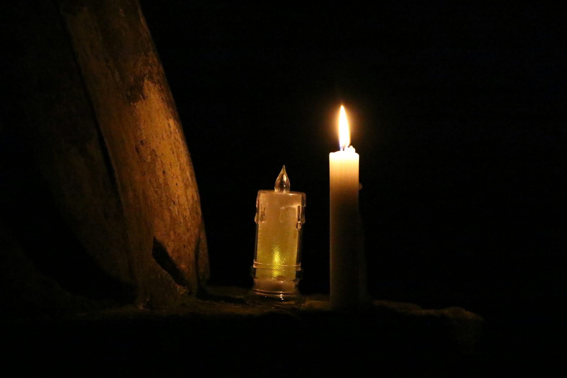 Deux bougies allumées dans l'obscurité, sur fond sombre.