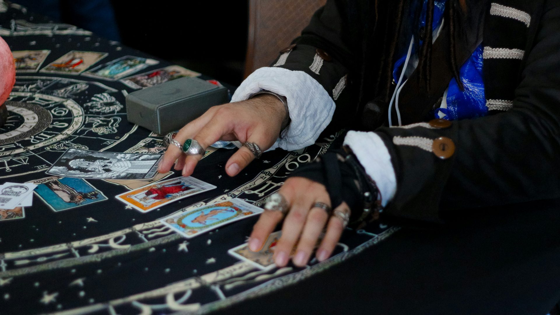 Des mains disposent des cartes de tarot sur un tissu à motifs célestes.